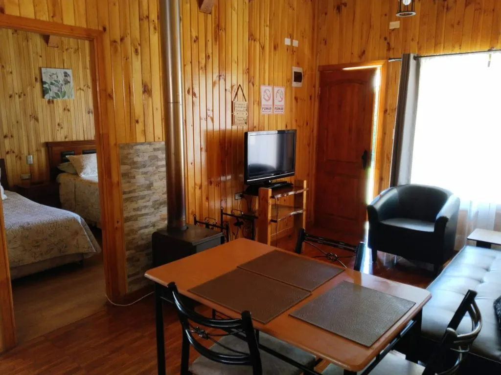 Cocina equipada con mesón de madera y comedor en cabaña Fabi Salto del Laja