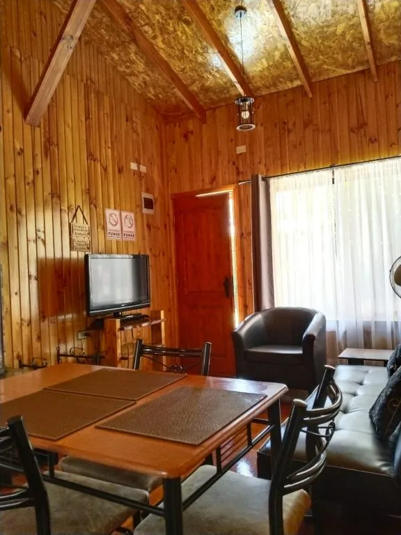Dormitorio con cama matrimonial y ventana con vista al jardín en cabaña Fabi
