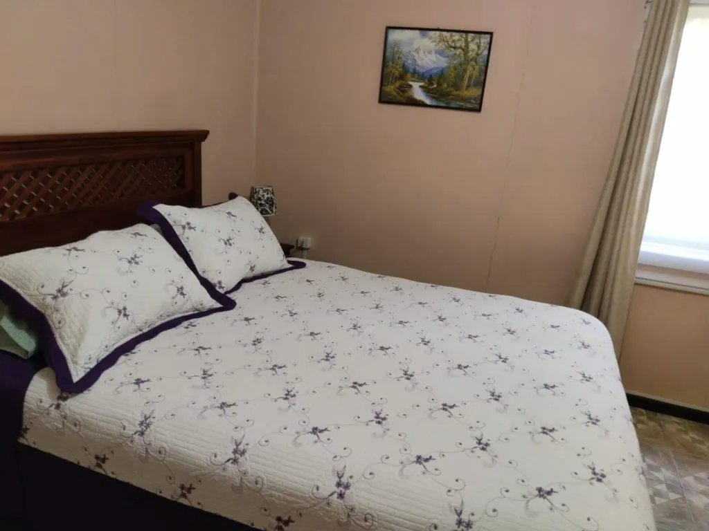 Dormitorio con cama matrimonial y cama individual con paredes de madera